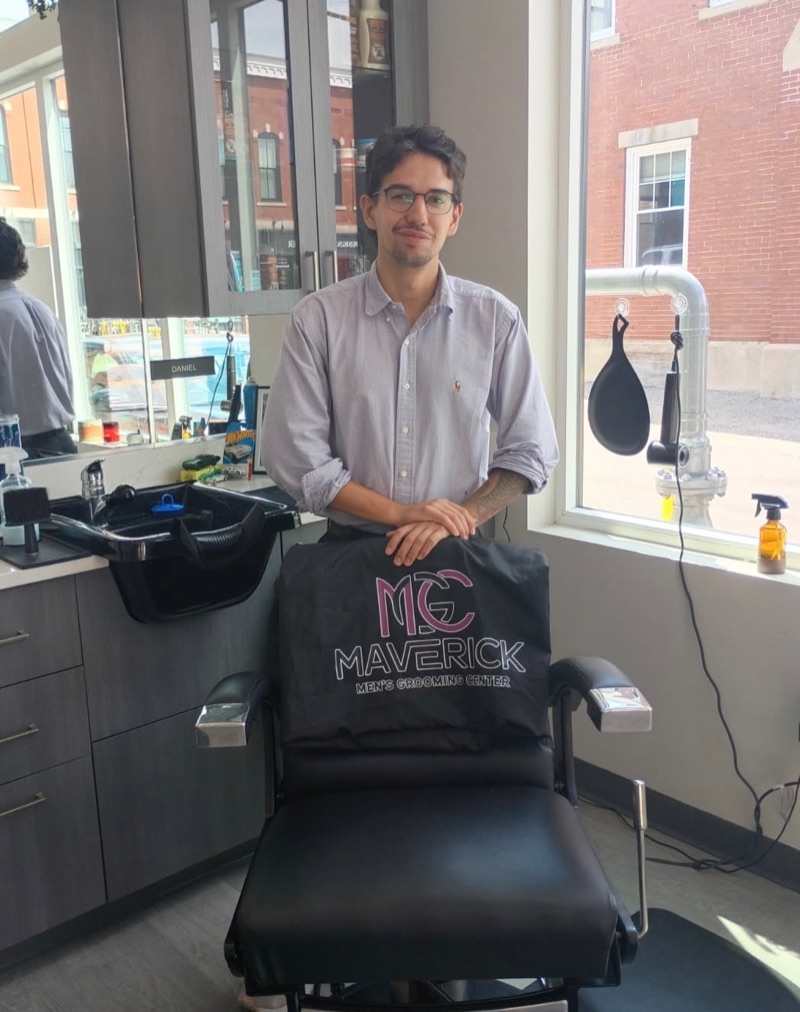 Barber Daniel DaSilva standing behind a Maverick barber chair