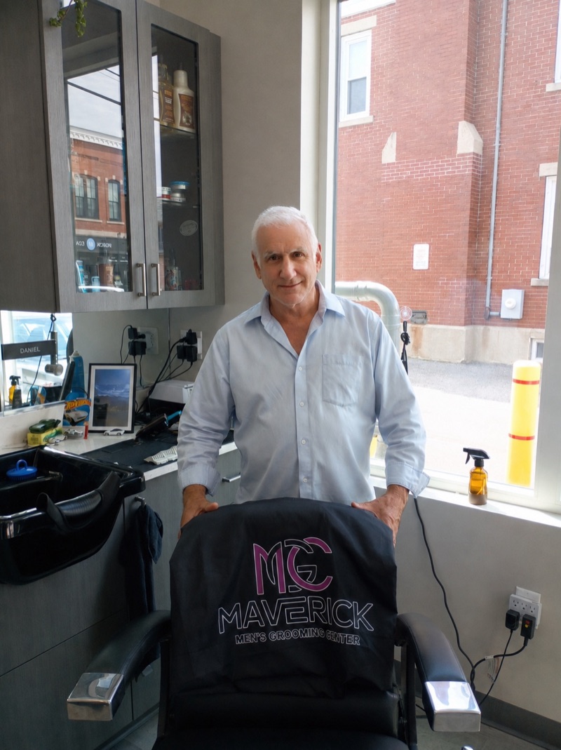 Barber Greg Meleones standing behind a Maverick barber chair